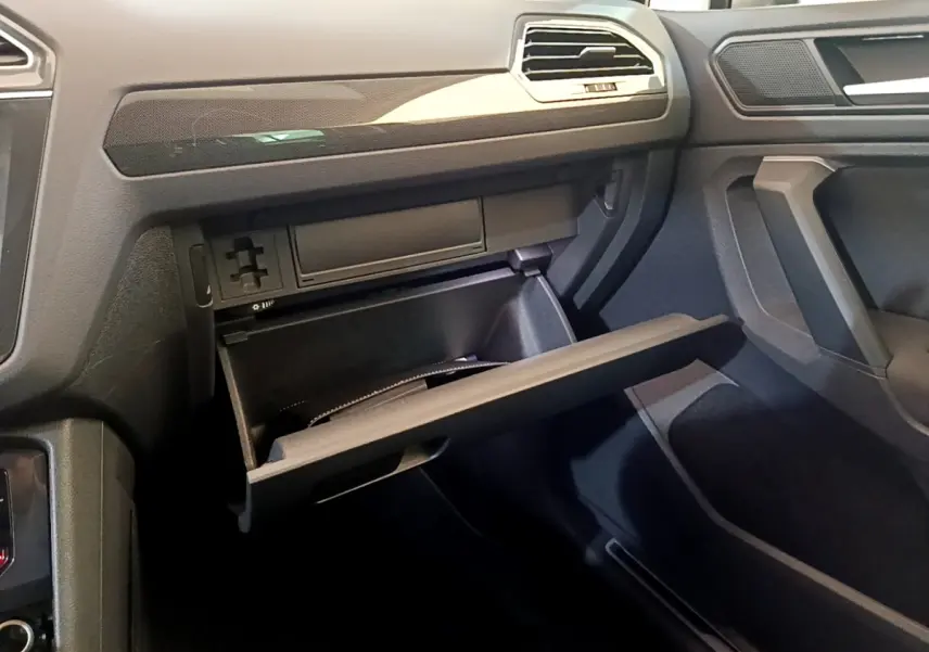 Vue intérieure côté passager du Volkswagen Tiguan gris clair 2021 avec boîte à gants ouverte et tableau de bord moderne.