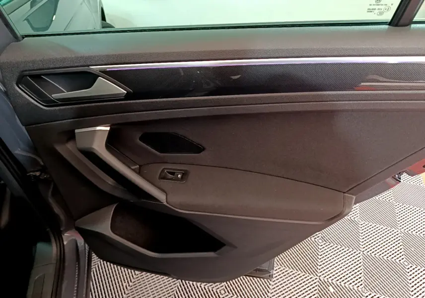 Vue intérieure côté gauche de la porte avant grise du Volkswagen Tiguan 2021 avec poignée argentée et garniture noire.