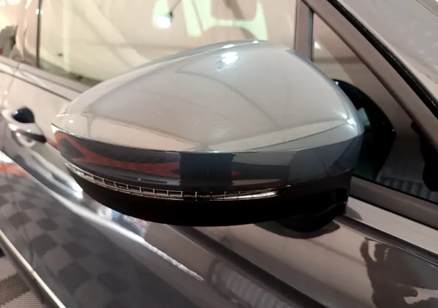 Gros plan sur le rétroviseur droit gris clair du Volkswagen Tiguan 2021 avec clignotant intégré visible.