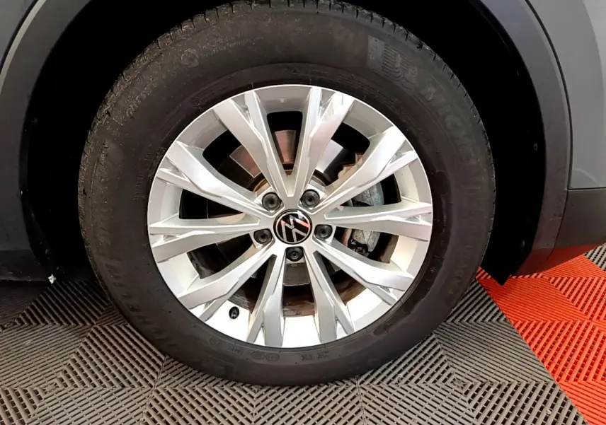 Gros plan sur la roue avant droite du Volkswagen Tiguan gris clair avec jante alliage à rayons multiples.
