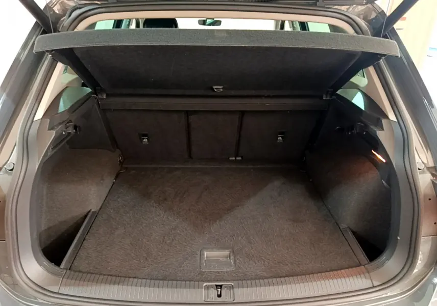 Coffre ouvert vu de l'arrière d'un Volkswagen Tiguan gris clair, montrant un espace de chargement propre et spacieux.