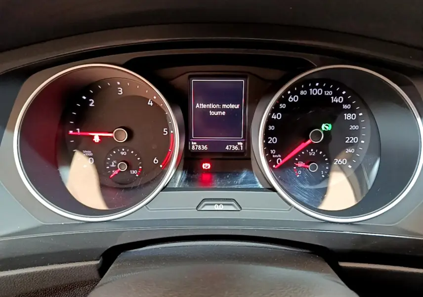 Vue rapprochée du tableau de bord du Volkswagen Tiguan gris clair, affichant les compteurs et un message moteur allumé.