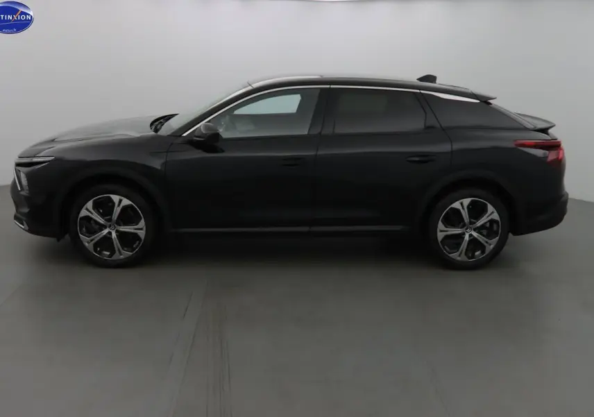 Profil côté gauche d'une Citroën C5 X noire métallisée 2022 avec jantes alliage bicolores et toit argenté.