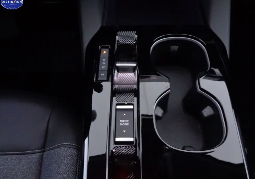 Vue rapprochée de la console centrale noire brillante du Citroën C5 X 2022, avec sélecteur de mode de conduite et porte-gobelets.