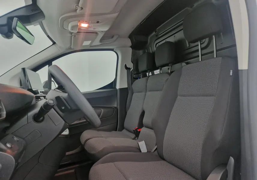 Vue intérieure côté conducteur du Peugeot Partner blanc 2025 avec banquette trois places et tableau de bord moderne.