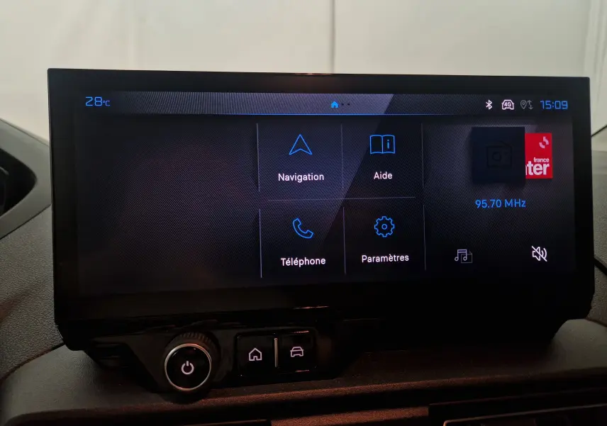 Écran tactile central du Peugeot Partner blanc 2025 affichant navigation, aide, téléphone et paramètres.