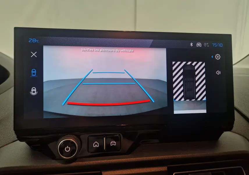 Écran de caméra de recul du Peugeot Partner blanc 2025 affichant les lignes de guidage et la vue aérienne du véhicule.