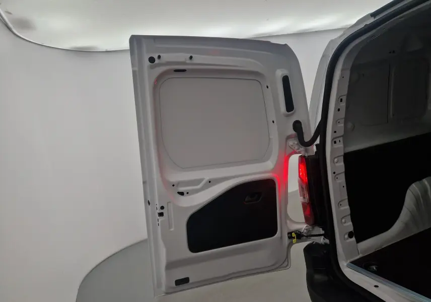 Vue rapprochée de la porte arrière gauche blanche du Peugeot Partner XL 2025 ouverte, avec feu arrière allumé.