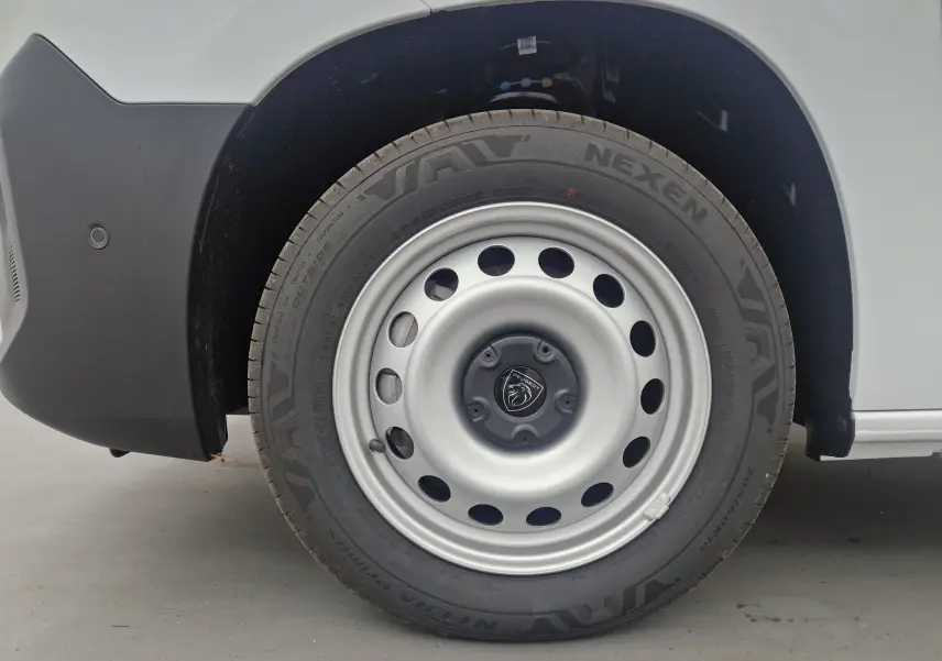 Gros plan sur la roue avant droite blanche du Peugeot Partner XL 2025 avec jante acier et logo Peugeot central.