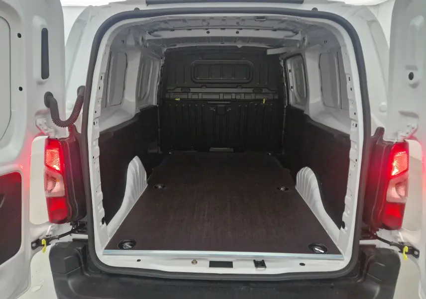 Vue arrière ouverte du Peugeot Partner blanc 2025, montrant l'espace de chargement avec plancher bois et parois protégées.