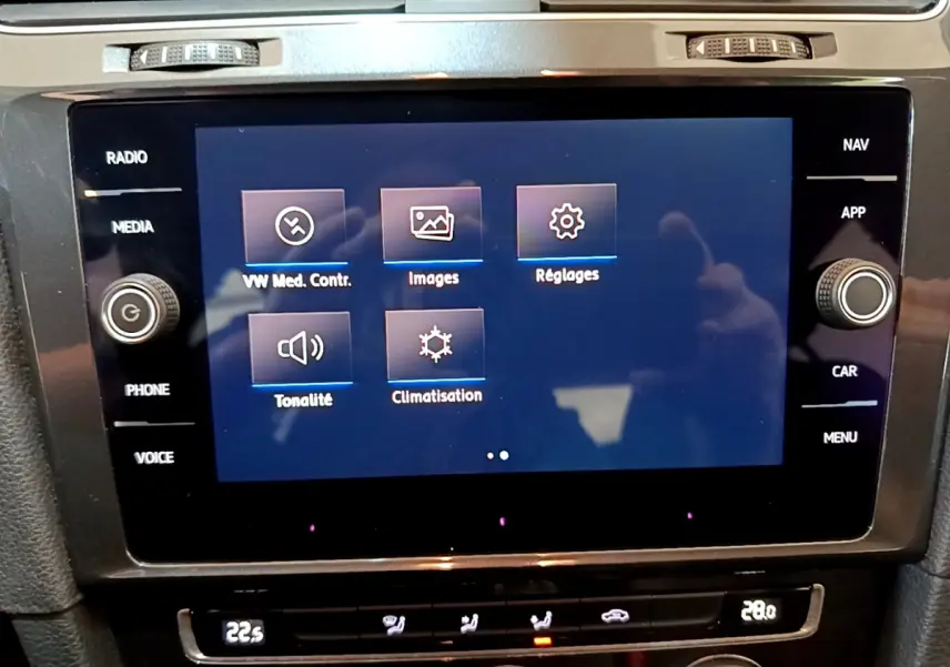 Gros plan sur l’écran tactile central et la console de climatisation de la Volkswagen Golf noire, vue intérieure avant.