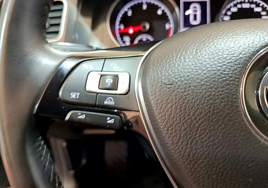 Gros plan sur le volant cuir noir de la Volkswagen Golf 2018, avec commandes multifonctions et tableau de bord en arrière-plan.