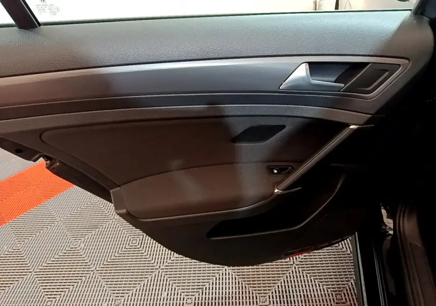 Vue intérieure côté droit de la porte avant noire de la Volkswagen Golf 2018 avec poignée argentée et panneau en bois.