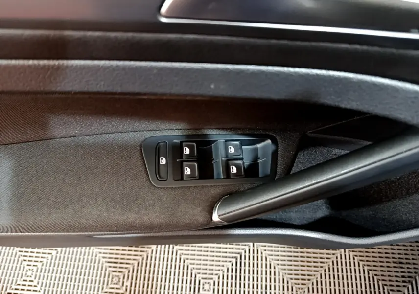 Gros plan sur la commande des vitres électriques côté conducteur d'une Volkswagen Golf noire, intérieur tissu noir.