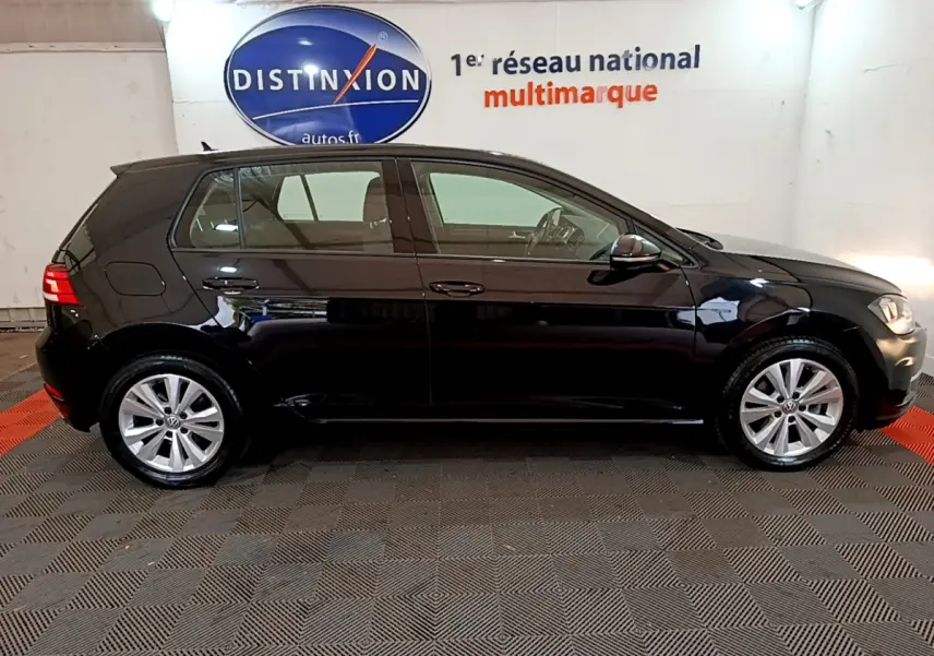 Profil côté gauche d'une Volkswagen Golf noire 2018, finition Confort Business, dans un showroom intérieur.