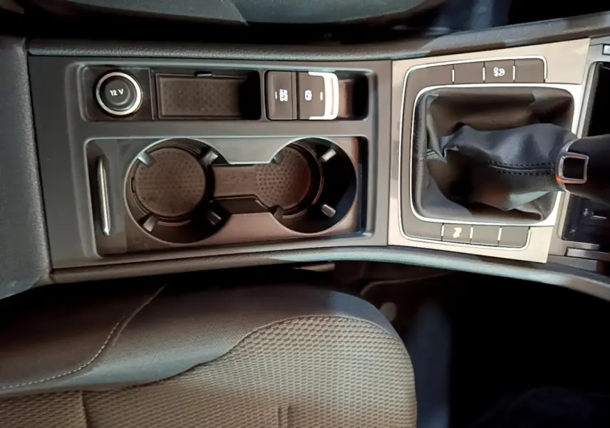 Vue rapprochée de la console centrale noire de la Volkswagen Golf 2018, avec levier de vitesses manuel et porte-gobelets.