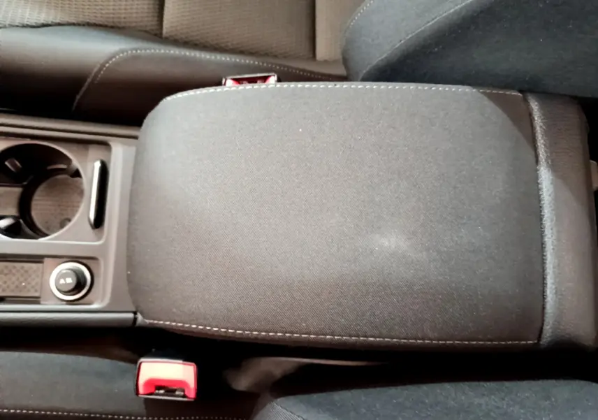 Vue rapprochée de l'accoudoir central noir et des porte-gobelets entre les sièges avant d'une Volkswagen Golf 2018.