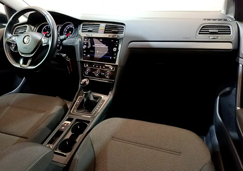 Vue intérieure avant droite de la Volkswagen Golf 1.6 TDI 2018 avec tableau de bord noir et boîte manuelle.