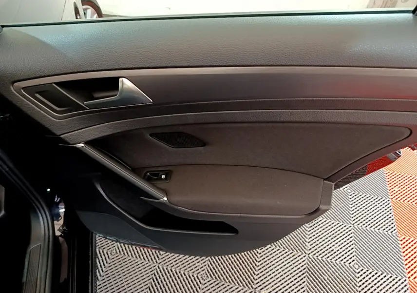 Vue intérieure côté gauche de la porte avant noire d'une Volkswagen Golf 2018 avec poignée argentée et habillage tissu.
