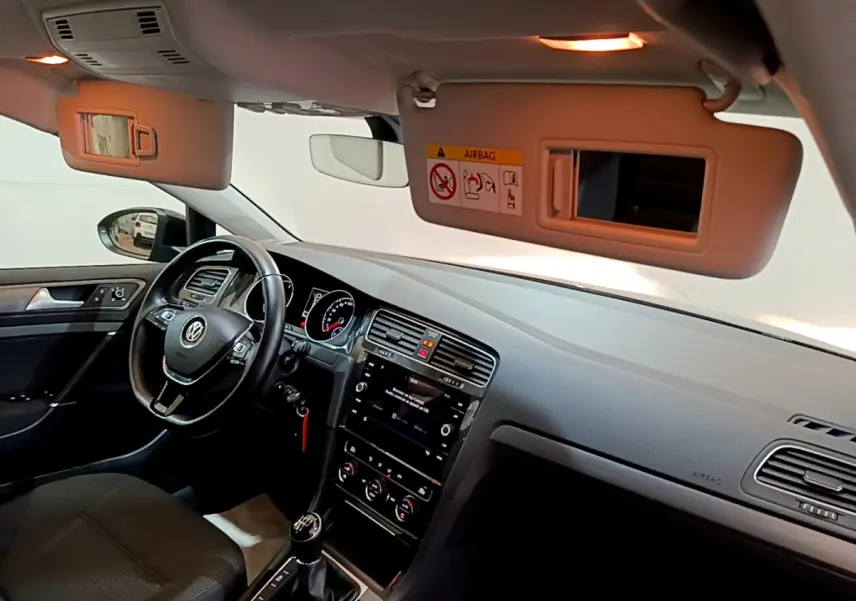 Vue intérieure côté conducteur de la Volkswagen Golf noire, montrant le volant cuir, tableau de bord et écran tactile central.