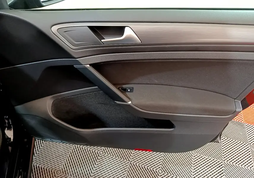 Vue intérieure côté gauche de la porte avant noire d’une Volkswagen Golf 2018 avec insert décoratif bois.