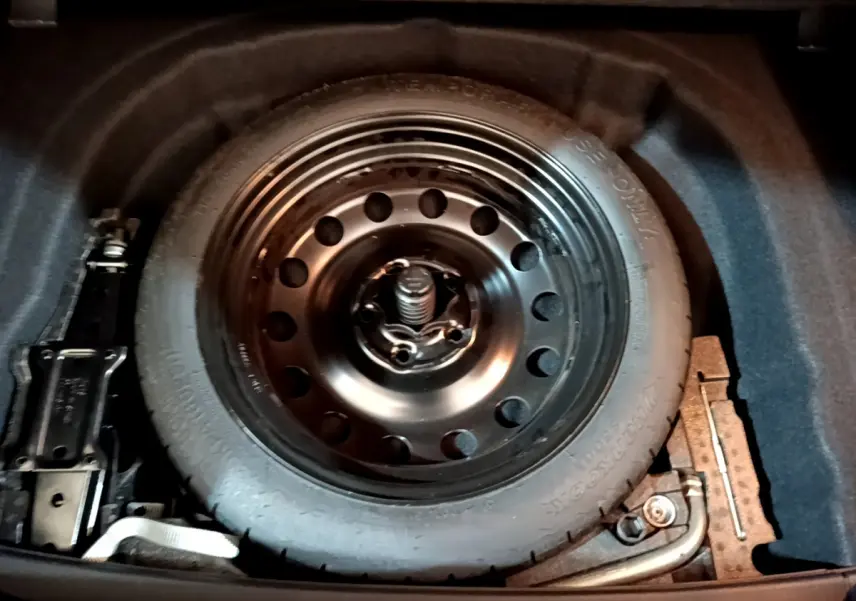 Gros plan sur la roue galette noire de secours dans le coffre d'une Volkswagen Golf noire de 2018.