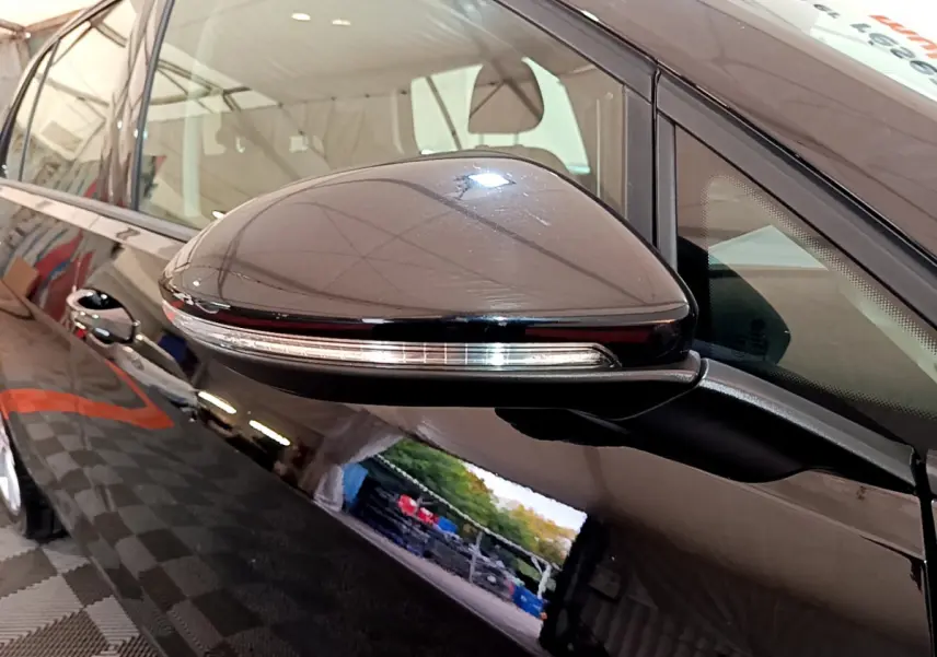 Rétroviseur noir avec clignotant intégré, vue rapprochée côté conducteur de la Volkswagen Golf noire 2018.