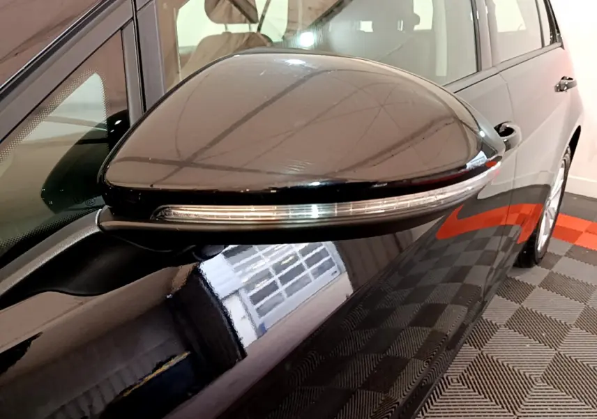 Gros plan sur le rétroviseur côté gauche noir brillant de la Volkswagen Golf 1.6 TDI 2018 avec clignotant intégré.