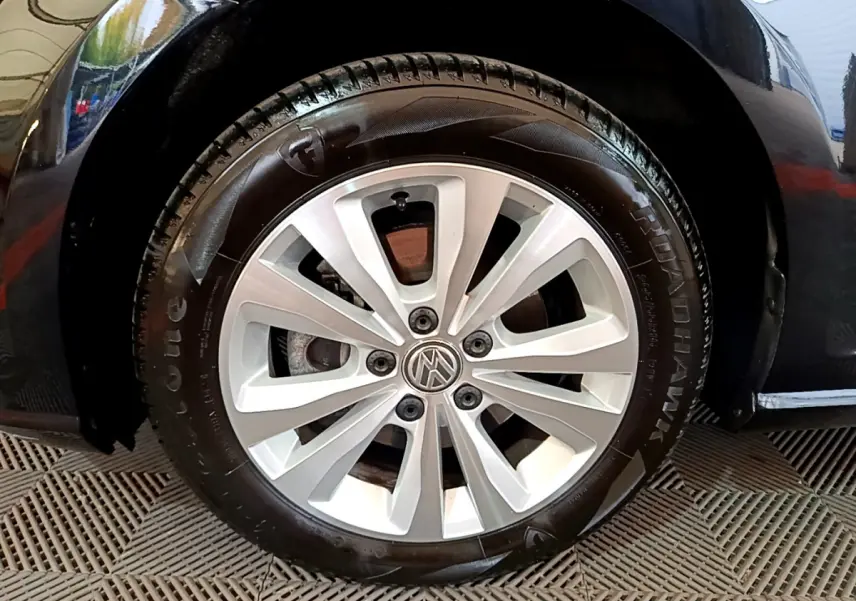 Gros plan sur la roue avant droite d'une Volkswagen Golf noire, jante alliage argentée à 10 branches.