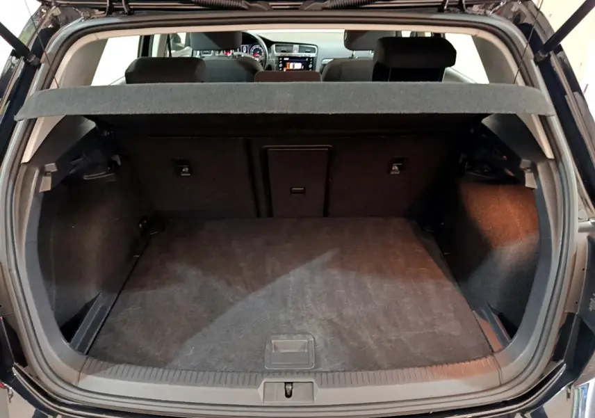 Vue arrière du coffre ouvert d'une Volkswagen Golf noire 2018, montrant l'espace de chargement et la tablette cache-bagages.
