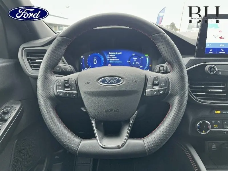 Vue intérieure centrée sur le volant cuir perforé avec surpiqûres rouges du Ford Kuga 2023, tableau de bord numérique visible.