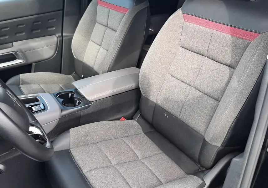 Vue intérieure côté gauche des sièges avant gris avec surpiqûres rouges et accoudoir central du Citroën C5 Aircross 2020.