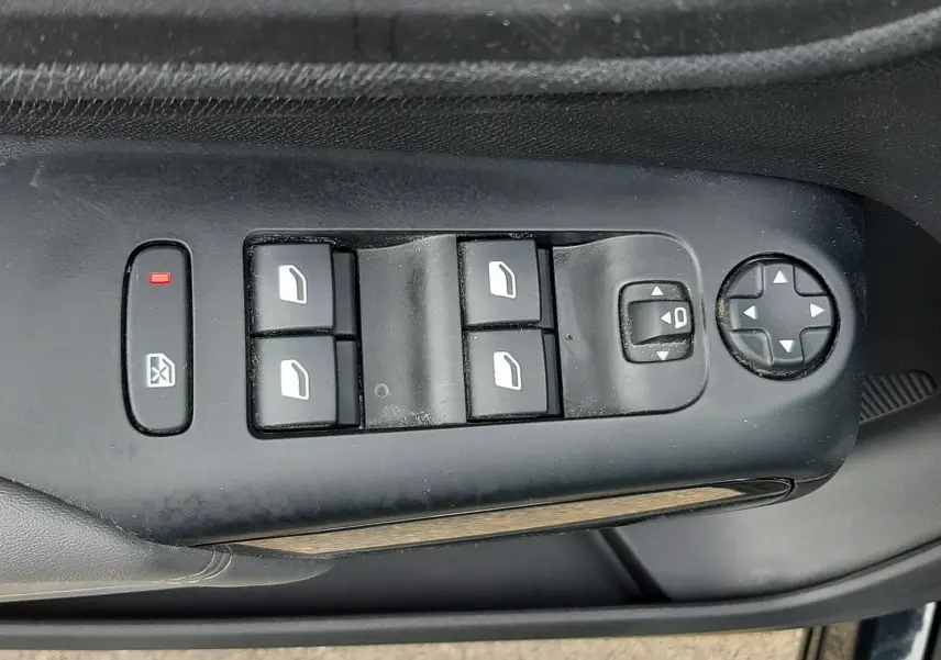 Gros plan sur la commande des vitres et rétroviseurs côté conducteur d’un Citroën C5 Aircross noir, avec boutons noirs et symbole blanc.