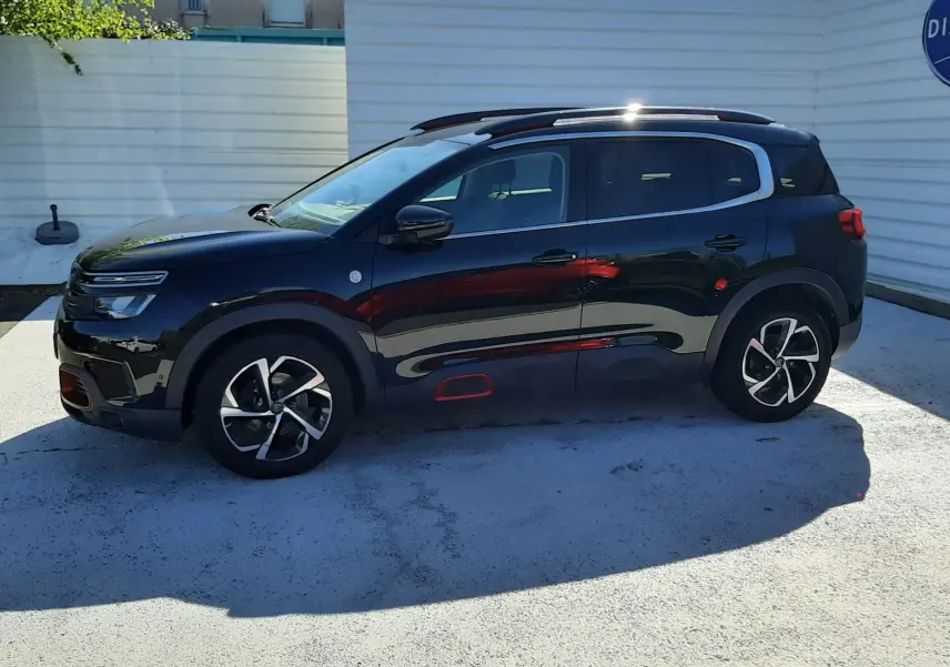 Citroën C5 Aircross noir en vue profil côté gauche, avec jantes bi-ton et inserts rouges distinctifs sur les bas de caisse.