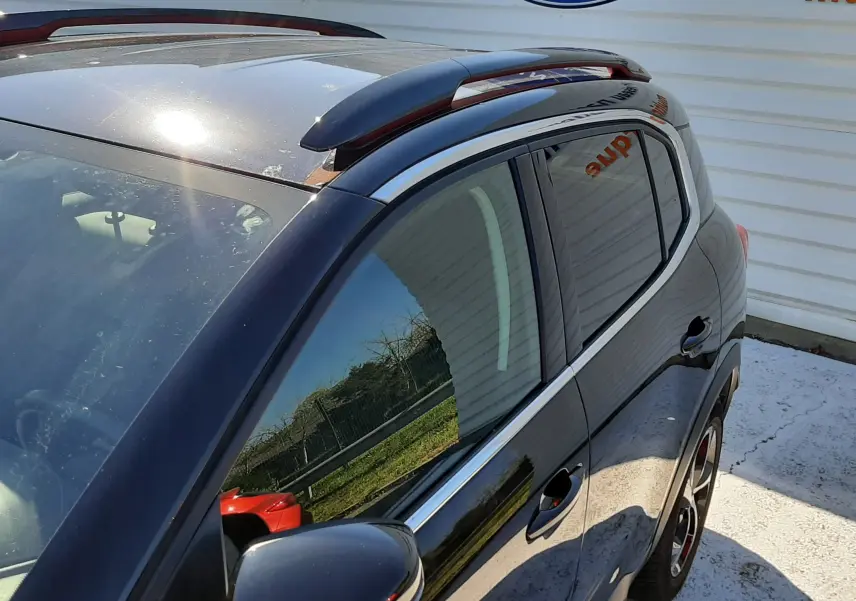 Vue de côté droit avant d'un Citroën C5 Aircross noir 2020 avec barres de toit et vitres teintées, reflet d'extérieur visible.