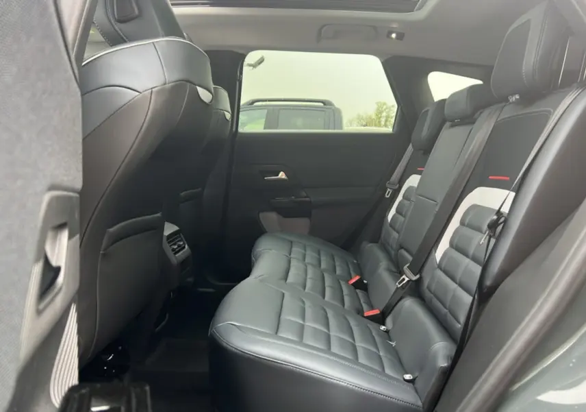 Vue latérale intérieure sur la banquette arrière cuir noir matelassé du Citroën C5 Aircross New Hybrid 2026 avec toit ouvrant panoramique.