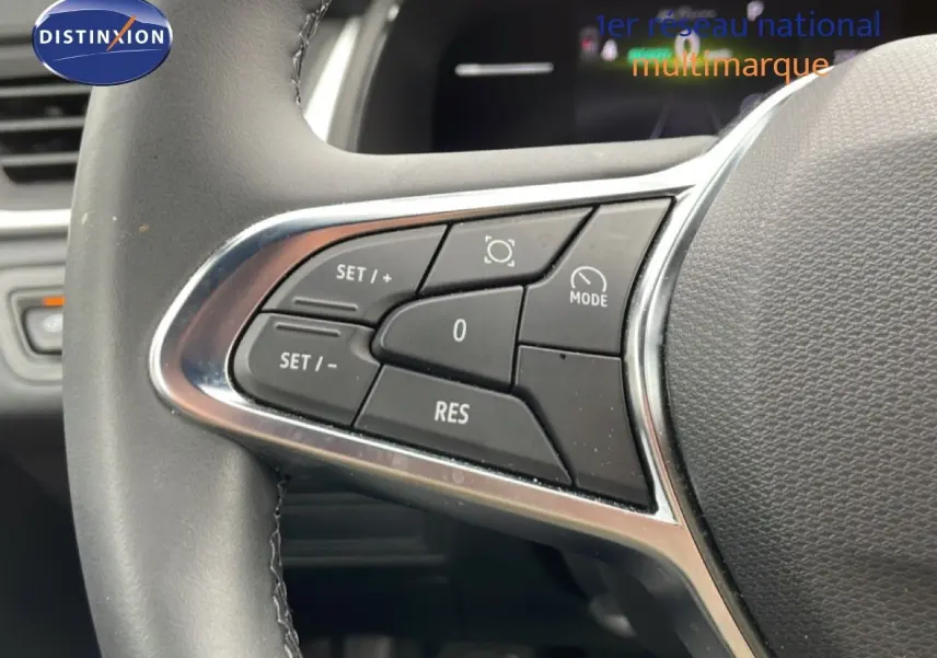Gros plan sur les commandes au volant à gauche du Renault Symbioz blanc nacré, mettant en valeur les boutons de régulateur de vitesse.