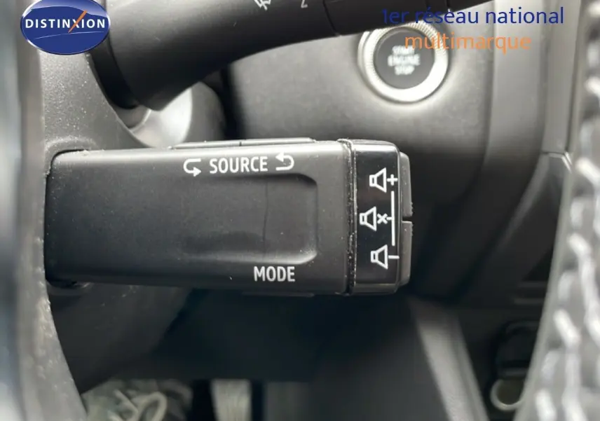 Gros plan sur la commande au volant du Renault Symbioz blanc nacré, mettant en valeur les boutons source et mode.