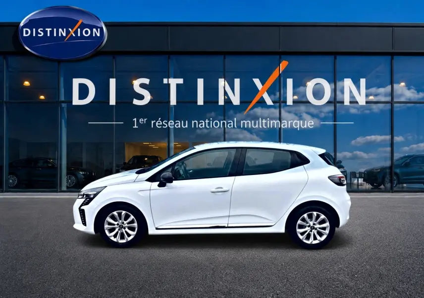 Profil droit d'une Renault Clio V blanche 2025, avec jantes alliage et poignées ton carrosserie, devant une vitrine Distinxion.