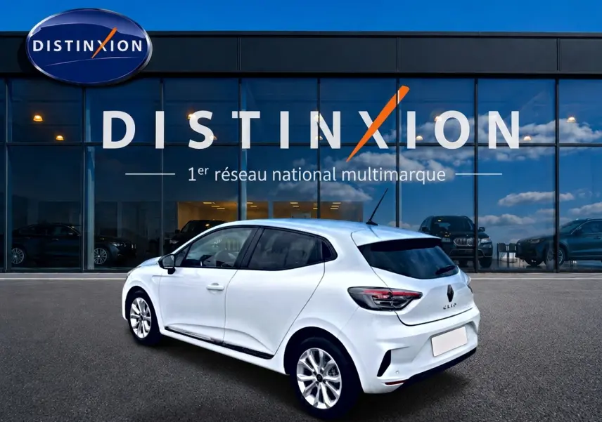 Vue 3/4 arrière droite d'une Renault Clio V blanche garée devant une vitrine avec logo Distinxion.
