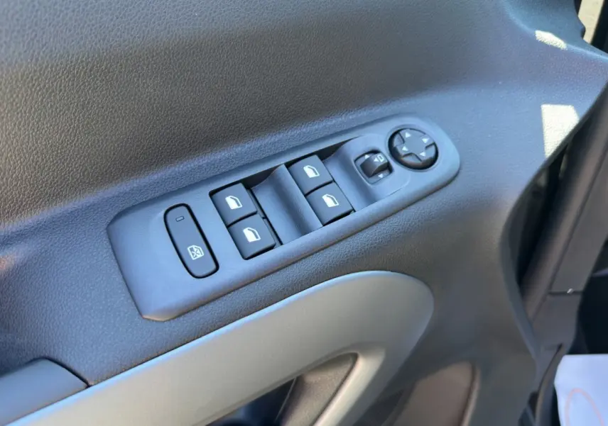 Vue rapprochée des commandes des vitres et des rétroviseurs sur la porte côté conducteur du Citroën Berlingo noir 2026.