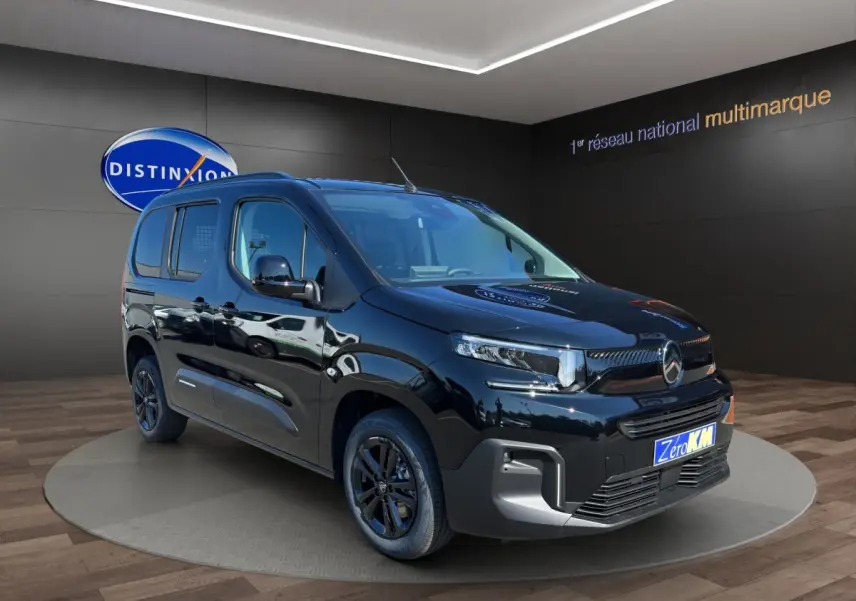 Vue 3/4 avant droite d’un Citroën Berlingo noir brillant, avec calandre moderne et jantes noires, en showroom.