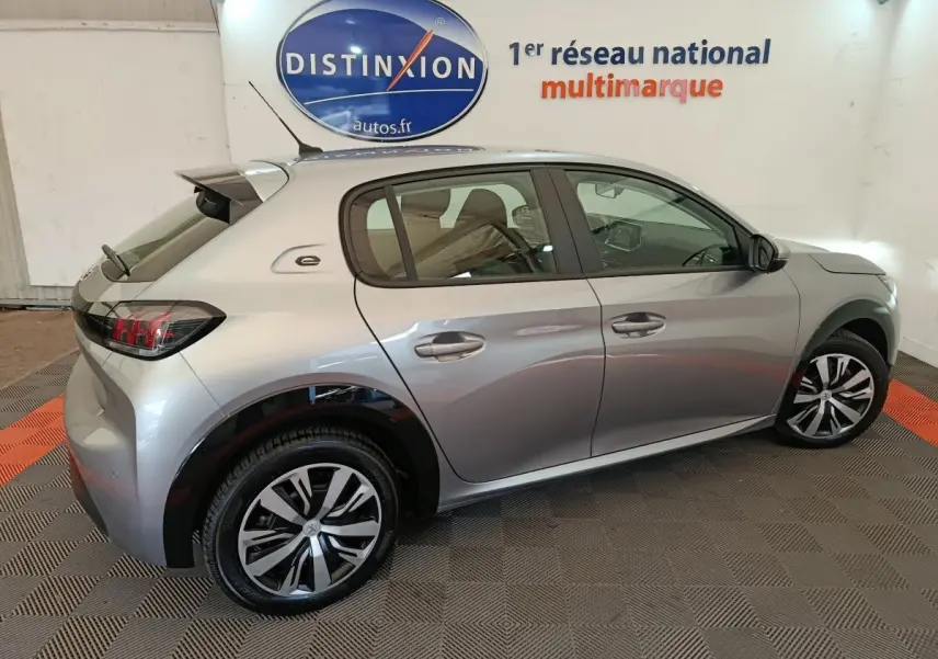 Profil droit d'une Peugeot 208 électrique Active Business gris clair avec jantes distinctives et logo "e" sur l'aile arrière.