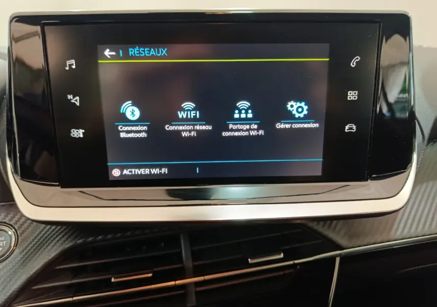 Écran tactile central affichant les options réseau dans l’habitacle d’une Peugeot 208 électrique gris clair.