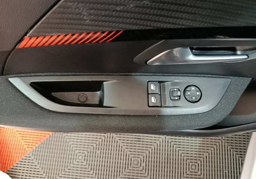 Gros plan sur la commande des vitres et rétroviseurs côté gauche de la porte intérieure d'une Peugeot 208 gris clair électrique.