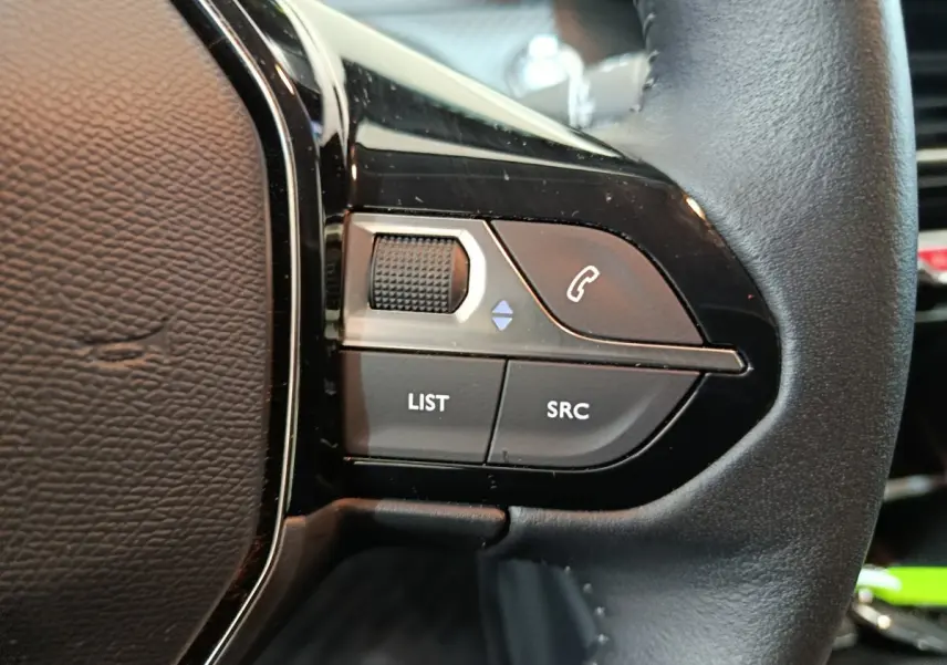 Gros plan sur les commandes gauche du volant cuir noir d'une Peugeot 208 Electrique Active Business 2020.