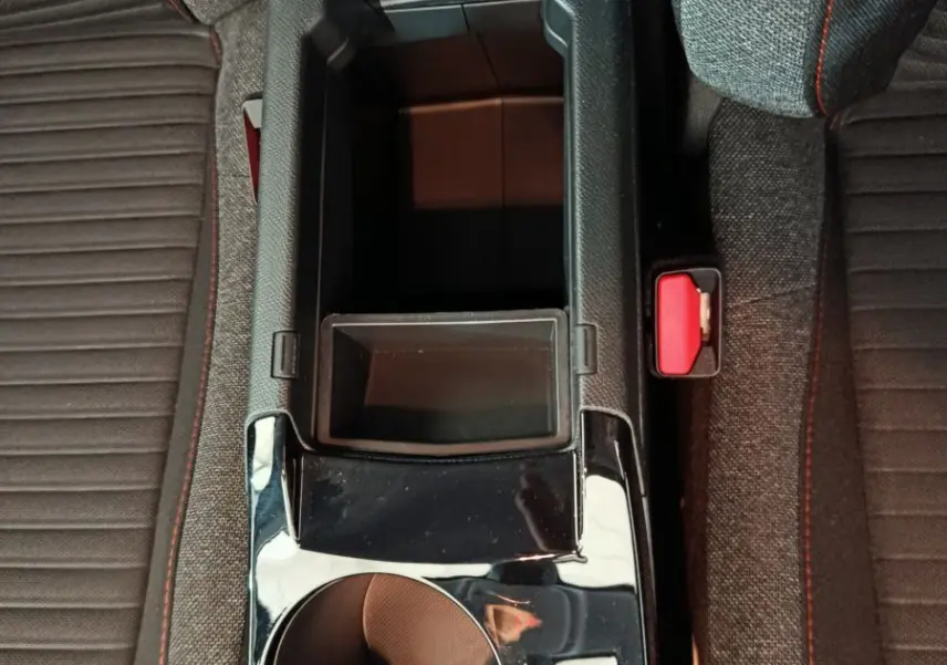 Vue plongeante sur la console centrale noire brillante et les sièges gris avec surpiqûres rouges d'une Peugeot 208 Electrique Active Business.