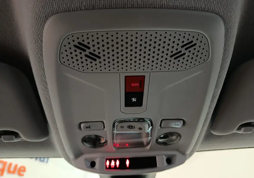 Vue en contre-plongée du plafonnier gris clair de la Peugeot 208 électrique avec bouton SOS rouge et éclairages intégrés.