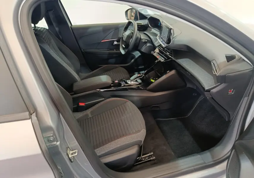 Intérieur côté conducteur de la Peugeot 208 électrique gris clair, avec tableau de bord moderne et écran tactile central.