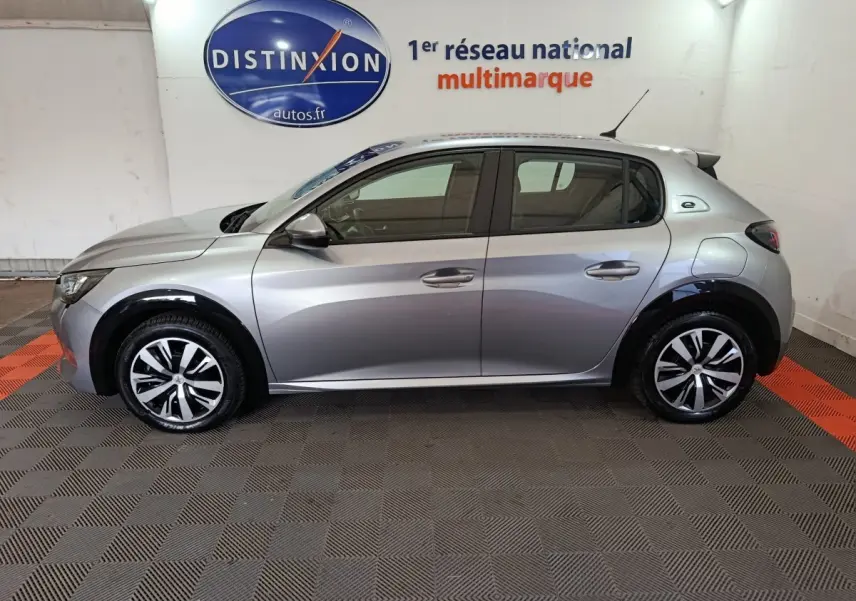 Peugeot 208 électrique gris clair vue de profil côté gauche, avec jantes stylisées et logo "e" de la version électrique.